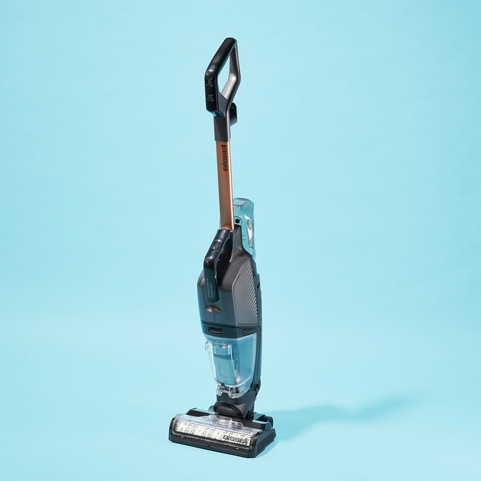 Vacuum cleaner stands upright, angled slightly left, against a pale blue background.