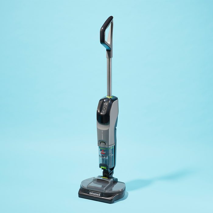 A standing vacuum cleaner appears idle against a bright blue background. The name 