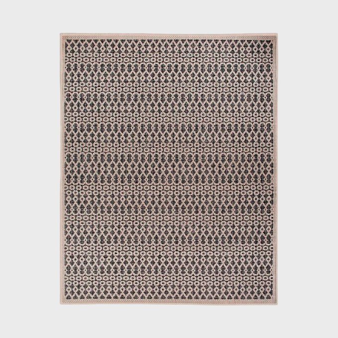 Rug displaying a repeating geometric pattern with dark and light colors, set against a plain white background.