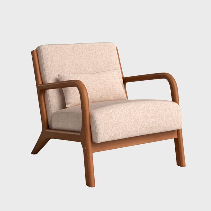 Wooden armchair rests on gray background, featuring light beige cushions and a comfy design.