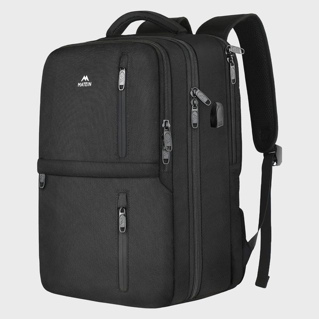 A black backpack stands upright with multiple zipped compartments in a studio setting. The logo 