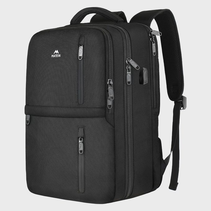 A black backpack stands upright with multiple zipped compartments in a studio setting. The logo 
