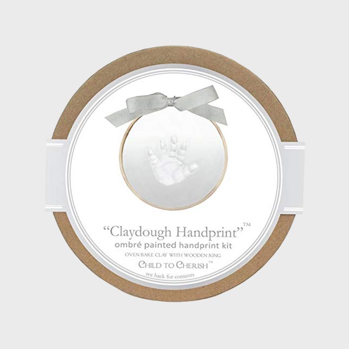 Circular clay handprint kit, features a baby handprint impression, adorned with a ribbon, labeled 