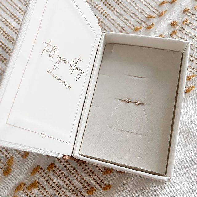 Stud earrings rest in a jewelry box with text reading, 