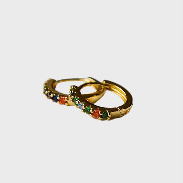 Gold hoop earrings adorned with multicolored gemstones are resting on a plain white background.