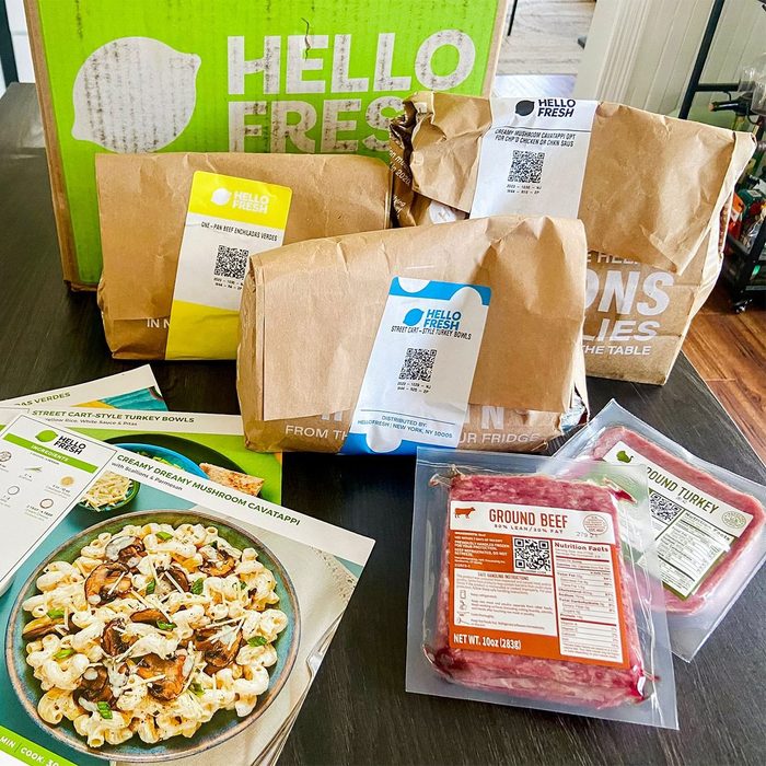 Food packages rest on a table, labels visible. A large green box with 