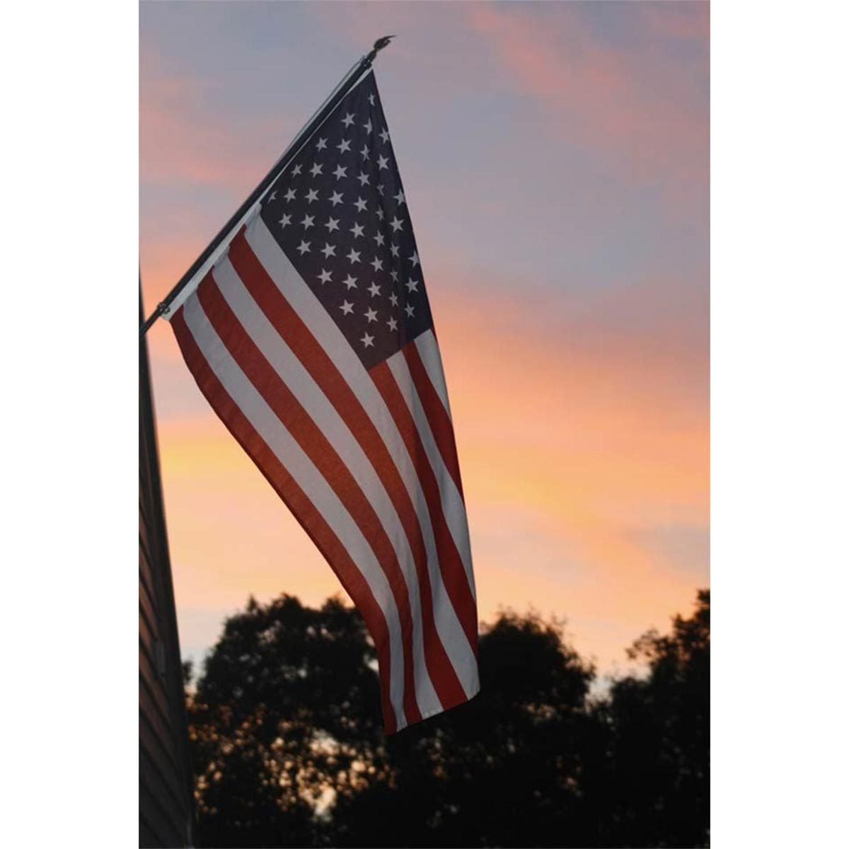 A flag hangs, displaying stars and stripes against a sunset sky with silhouetted trees in the background.