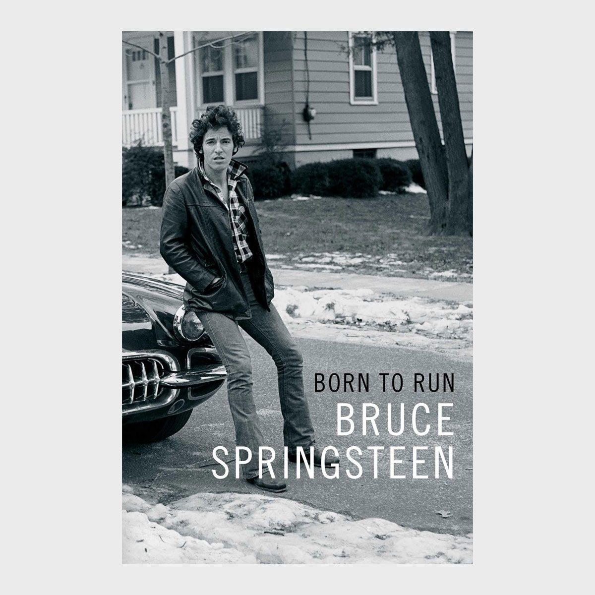 Man leans against car on snowy street; text reads, "BORN TO RUN BRUCE SPRINGSTEEN." Urban backdrop with house and trees in the background.