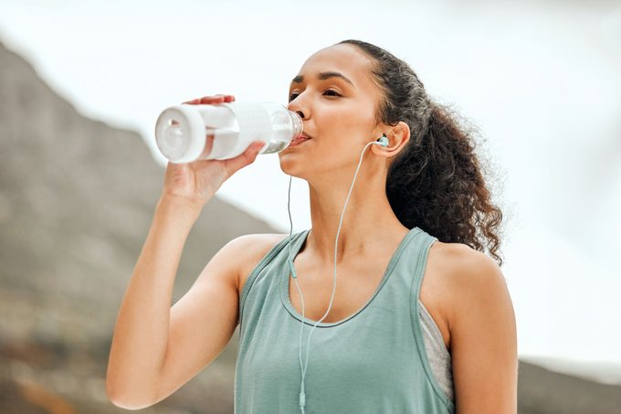 Shot of a young woman taking a break from working out to drink water