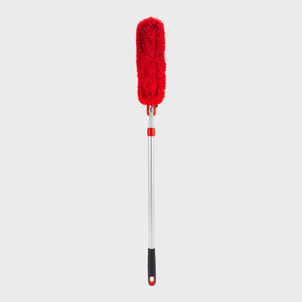 Red duster with fluffy head attached to a long metallic handle, standing upright against a plain gray background.