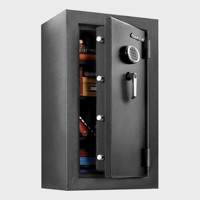 Safe door is slightly open, revealing shelves with miscellaneous items inside, against a plain backdrop.