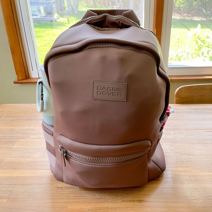 Backpack sits on a wooden table, holding a water bottle. 
