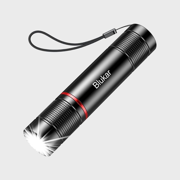 Flashlight emitting bright light, hanging by a strap, on plain background. Text: 
