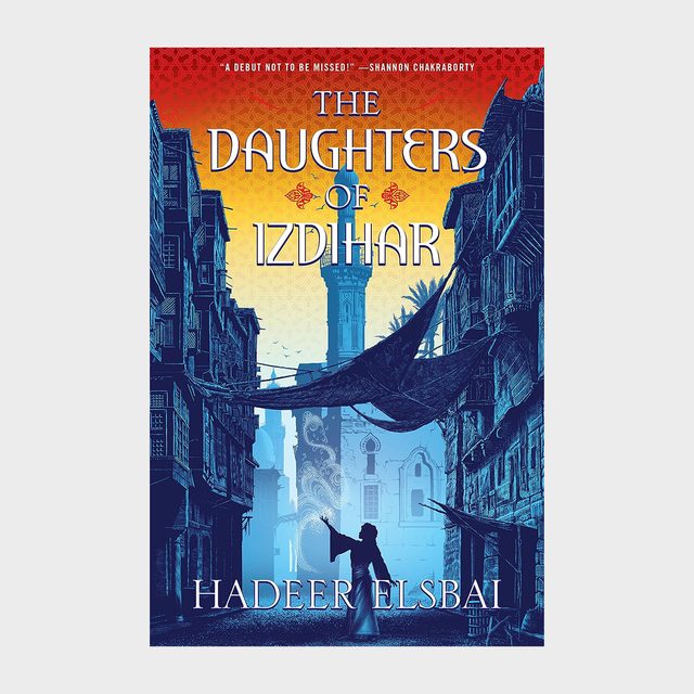 A person gestures under draped fabric in a narrow, historical street. Buildings frame the scene with a distant tower visible. Text: 