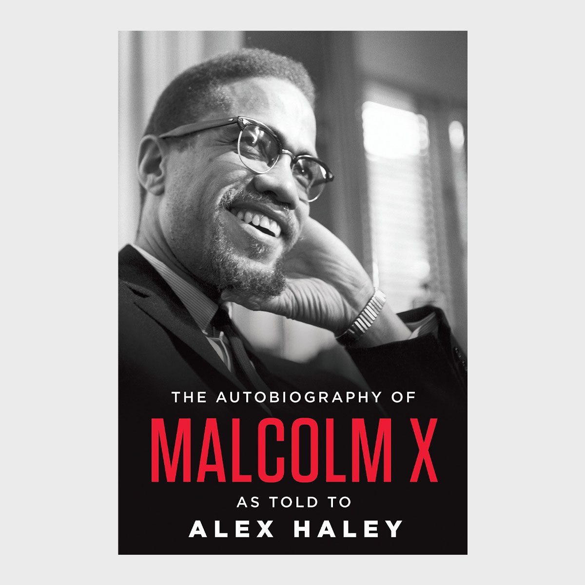A smiling man rests his head on his hand, wearing glasses and a suit. Text: "THE AUTOBIOGRAPHY OF MALCOLM X AS TOLD TO ALEX HALEY."