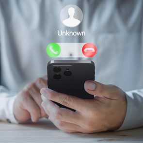 A person holds a smartphone showing a call from 
