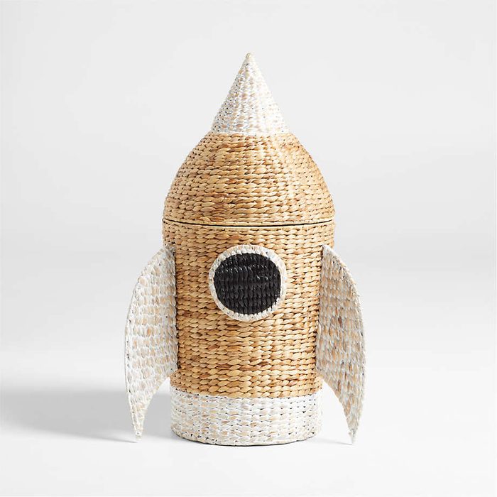 Wicker rocket-shaped basket standing upright against a plain background, featuring two lateral fins and a central round window detail.
