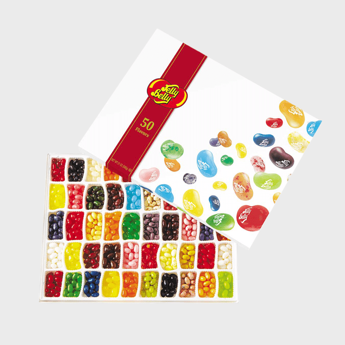 Jelly beans sit assorted by color in a box with a lid displaying various flavors; labeled 