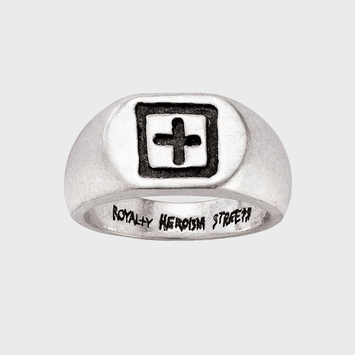 Silver ring displays a black cross within a square; interior features engraved text: 