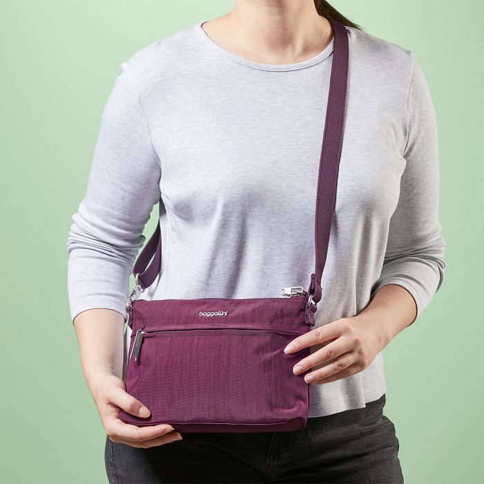 Person wearing a gray shirt holds a purple shoulder bag labeled 