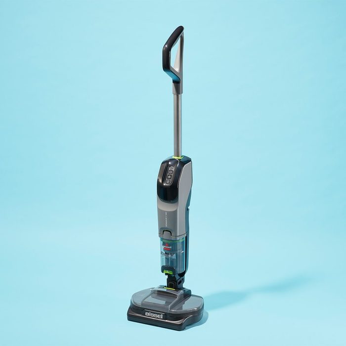 Vacuum cleaner stands upright on a blue background, featuring a sleek design and labeled 