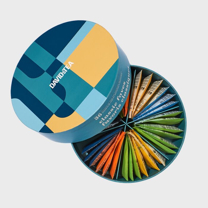 Round box displays colorful tea packets, arranged in segments. Lid shows abstract blue and yellow design with 