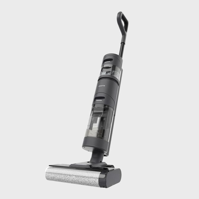 Vacuum cleaner stands upright, showcasing a sleek design and transparent compartments, set against a plain gray background.