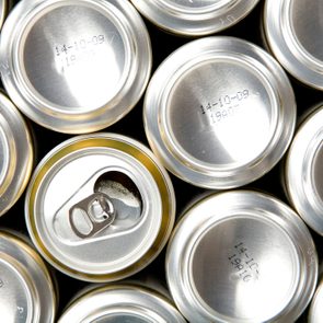 Cans arranged in a grid, one opened, viewed from above; text on several reads 