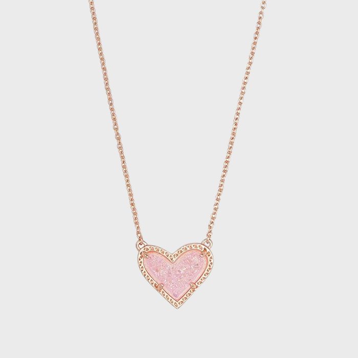 Heart-shaped pink pendant hangs on a delicate gold chain, against a plain white background.