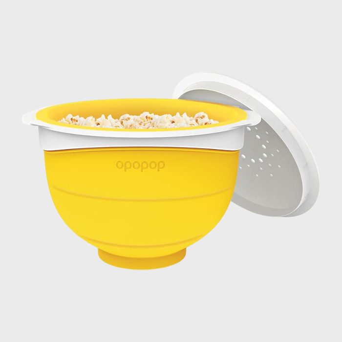 Yellow popcorn bowl holds popcorn, lid partially open, against gray background. Text reads 