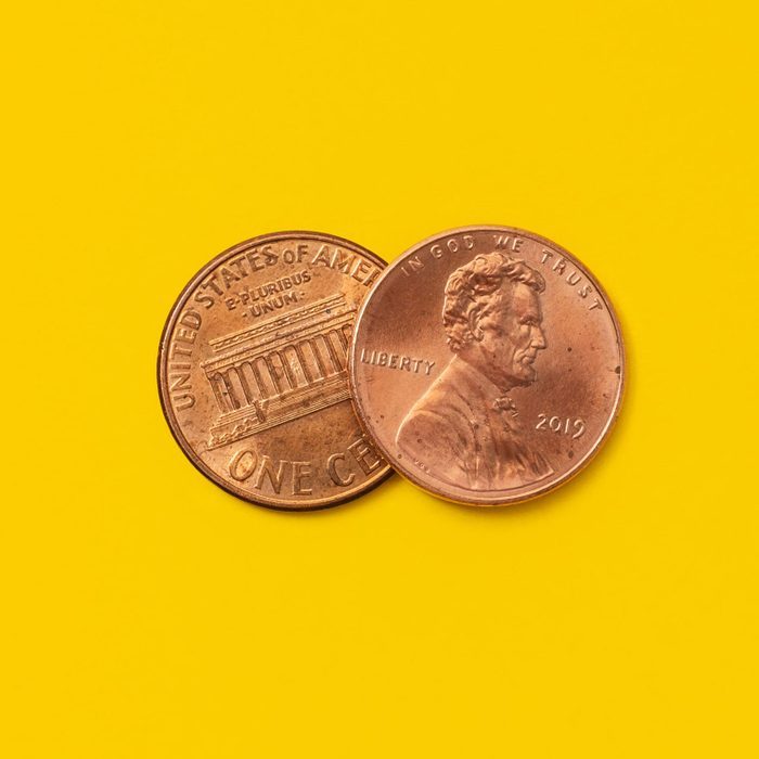 Two pennies lying on a yellow surface; one shows Lincoln's profile, the other displays the Lincoln Memorial.