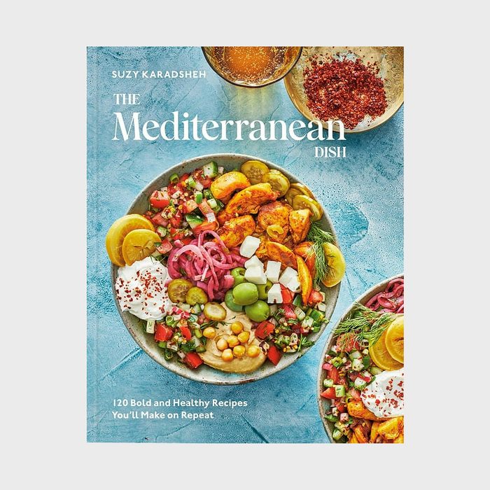 A vibrant Mediterranean dish with various colorful ingredients on a blue surface, accompanied by text promoting bold, healthy recipes from Suzy Karadsheh.
