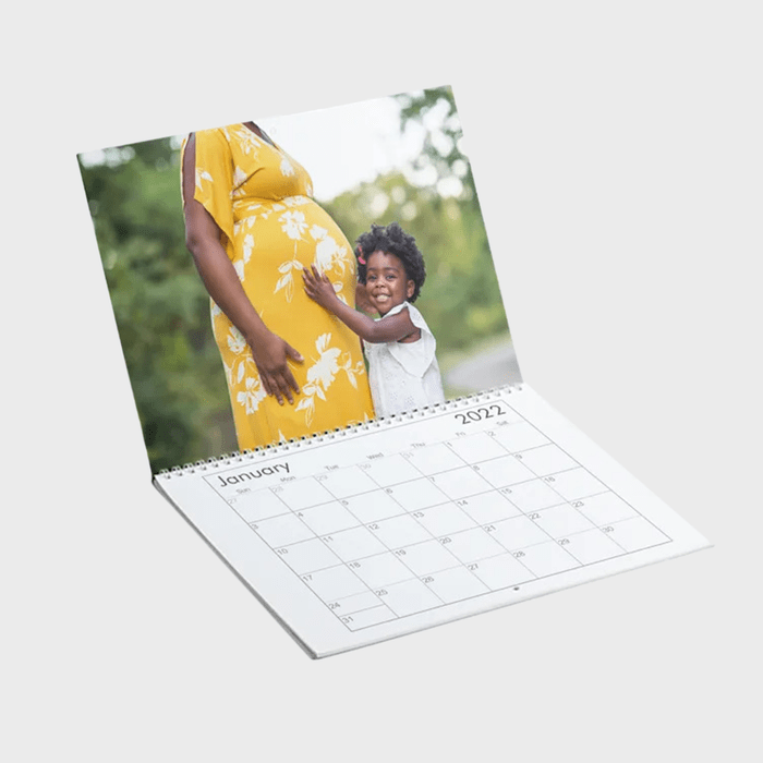 Calendar shows January 2022; child hugs pregnant person in yellow dress in an outdoor setting, creating a warm, familial moment.