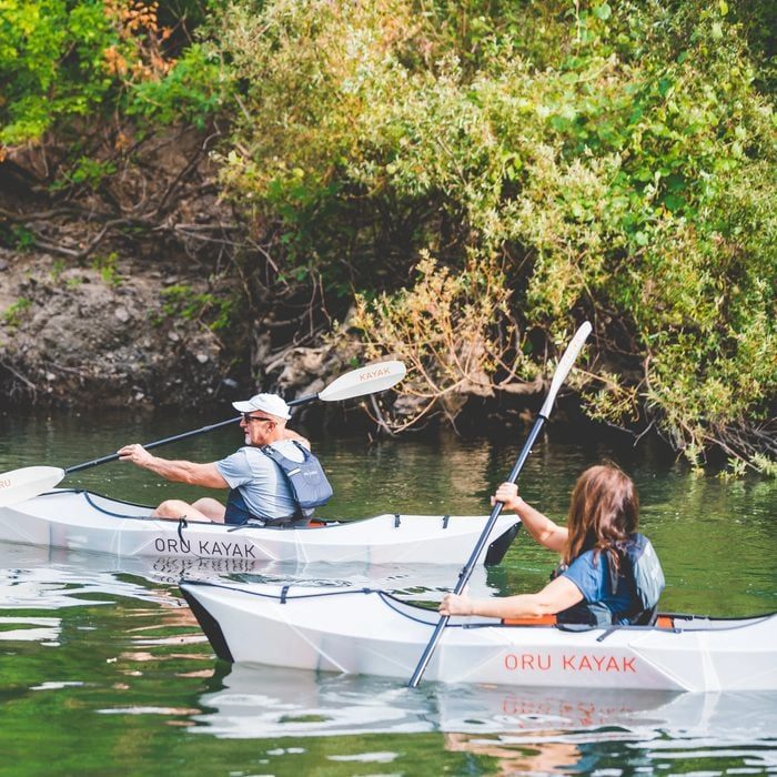 Kayaks glide through calm water; two people paddle amidst lush greenery with 
