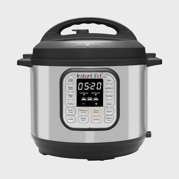 Pressure cooker displays digital timer, buttons surround display, stainless steel body with black lid, indoors.