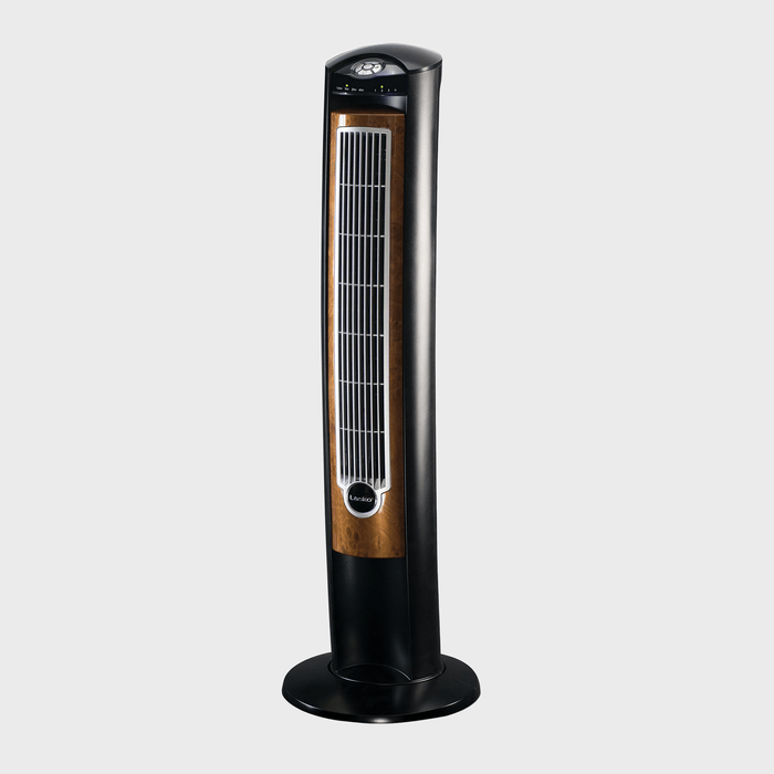 A tower fan stands upright, displaying control buttons on top, featuring a sleek black and wood pattern design, set against a plain gray backdrop.