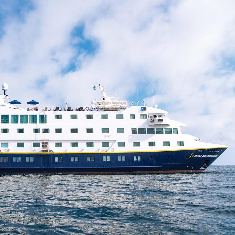 Ship cruising on calm sea, surrounded by a partly cloudy sky.