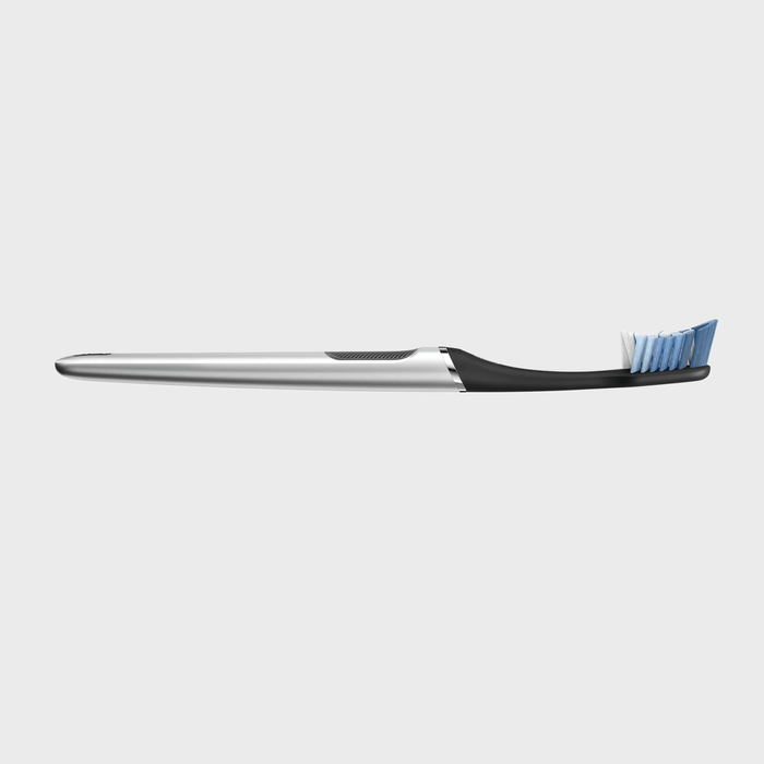 A sleek toothbrush with blue bristles lies horizontally on a plain white background.