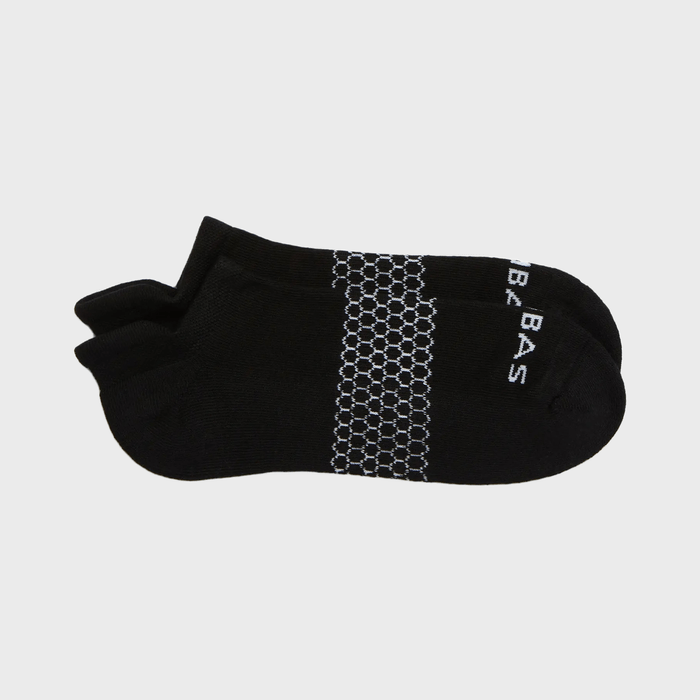 Black socks lie flat, featuring hexagonal patterns and white text on the toes, against a plain white background.