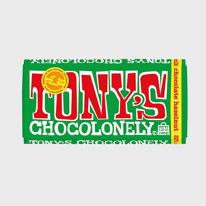 A green Tony's Chocolonely chocolate bar wrapper features bold red and white text. It highlights milk chocolate hazelnut flavor, weighing 6.35 oz (180 g).