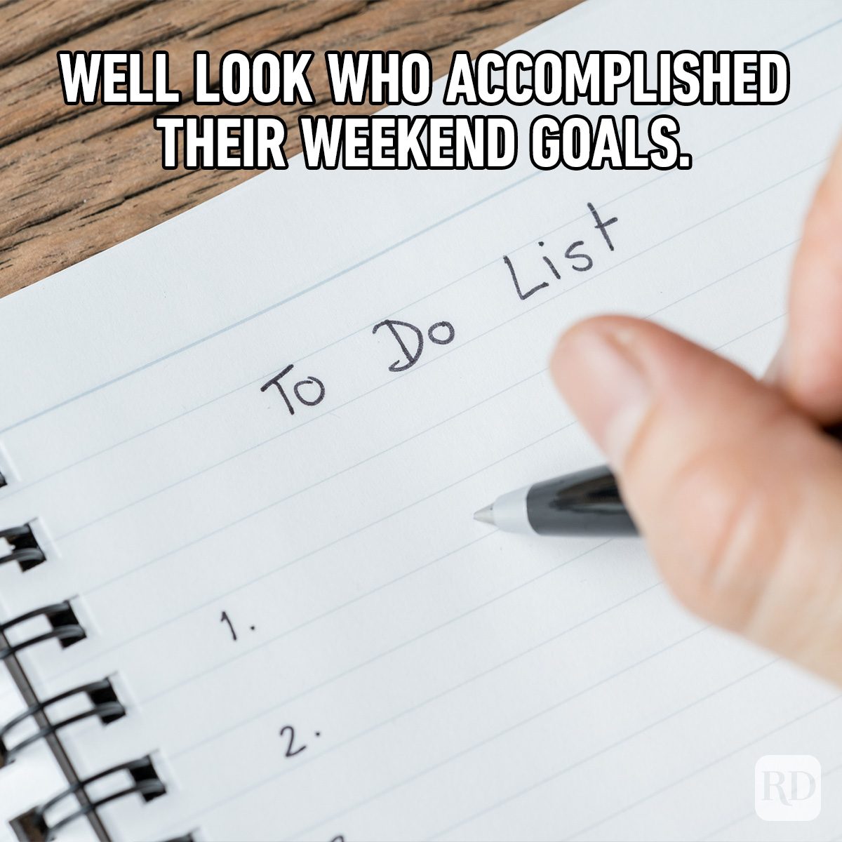 Hand writes on a "To Do List" in a notebook, against a wooden surface. Text above reads, "WELL LOOK WHO ACCOMPLISHED THEIR WEEKEND GOALS."