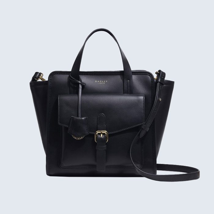 A black leather handbag rests against a plain background, featuring two handles, a front pocket with a buckle, and an adjustable shoulder strap.