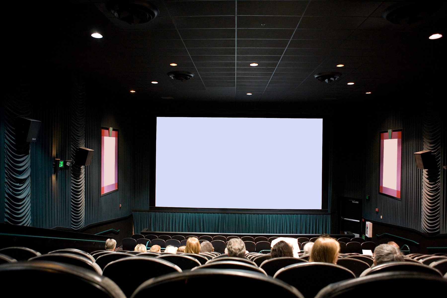 Movie screen remains blank, positioned in a dim theater; few people seated, waiting for a film to start.