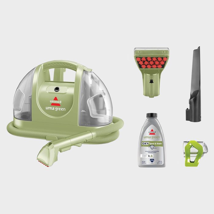 Green Bissell Little Green machine with attachments displayed, including solution bottle, brush nozzle, and hose, on a plain background.