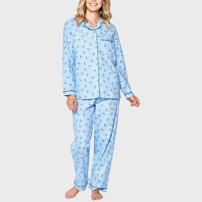 Person wearing blue floral pajamas stands smiling against a plain background.