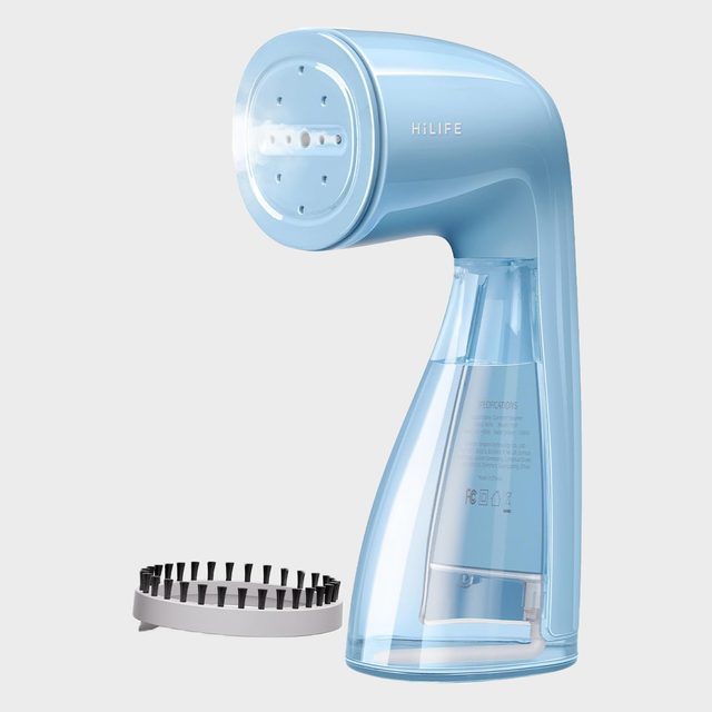 A blue handheld steamer stands upright beside a black bristle attachment on a plain background. The steamer is labeled 