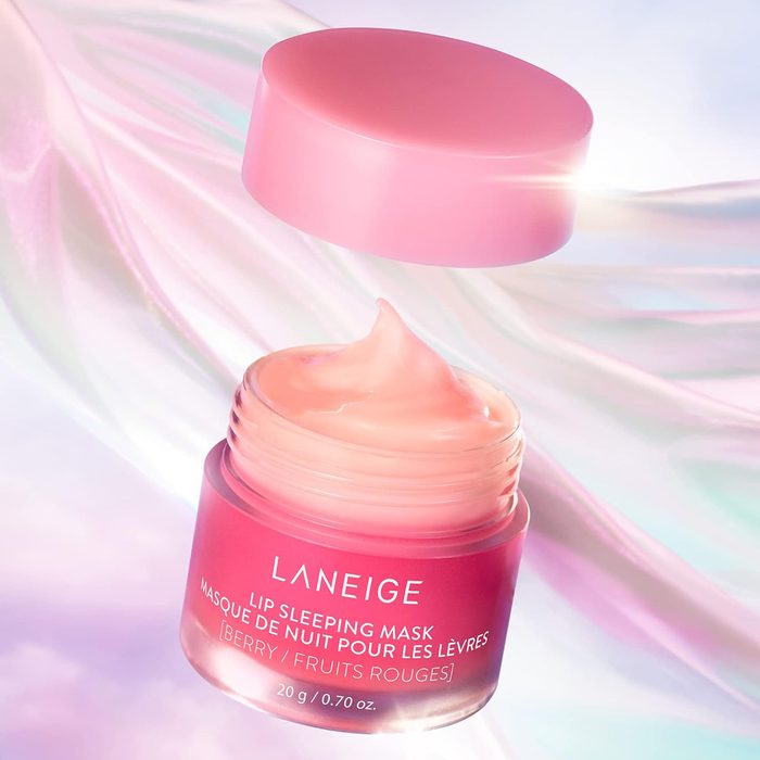 Jar of pink lip mask, with open lid floating above, against a shimmering pastel background. Text reads: 