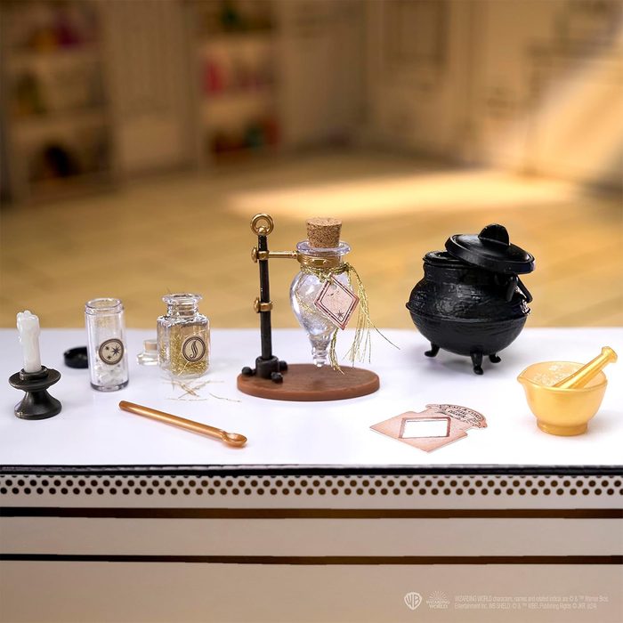 Glass bottles sit on a table alongside a cauldron, candle, and mortar, creating a potion-making scene in a cozy room.