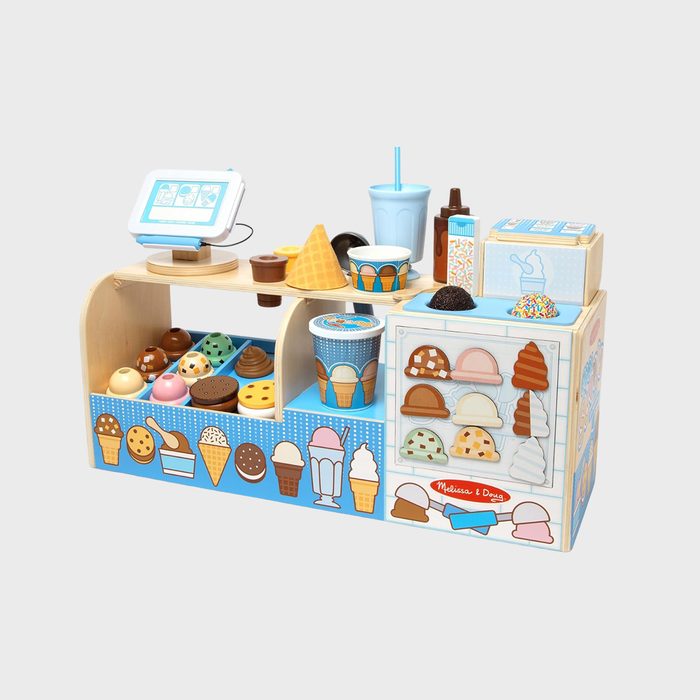 Toy ice cream counter displays assorted wooden cones and scoops, surrounded by illustrated packaging in a playful, colorful setting.