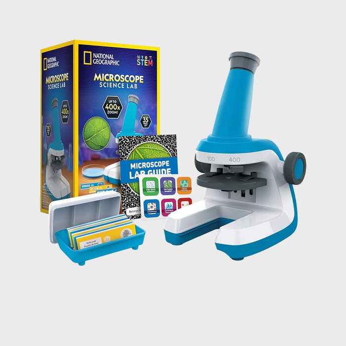 Microscope displayed with lab guide, slides, and box; set in educational context, emphasizing scientific exploration and learning tools.